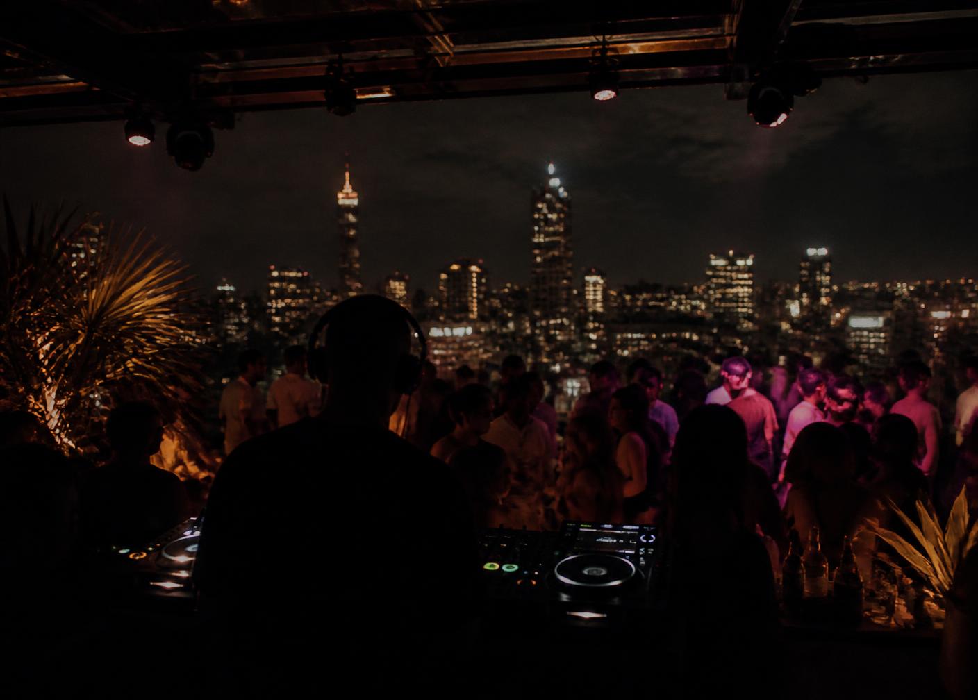 A rooftop party in Johannesburg with the city skyline behind the DJ booth